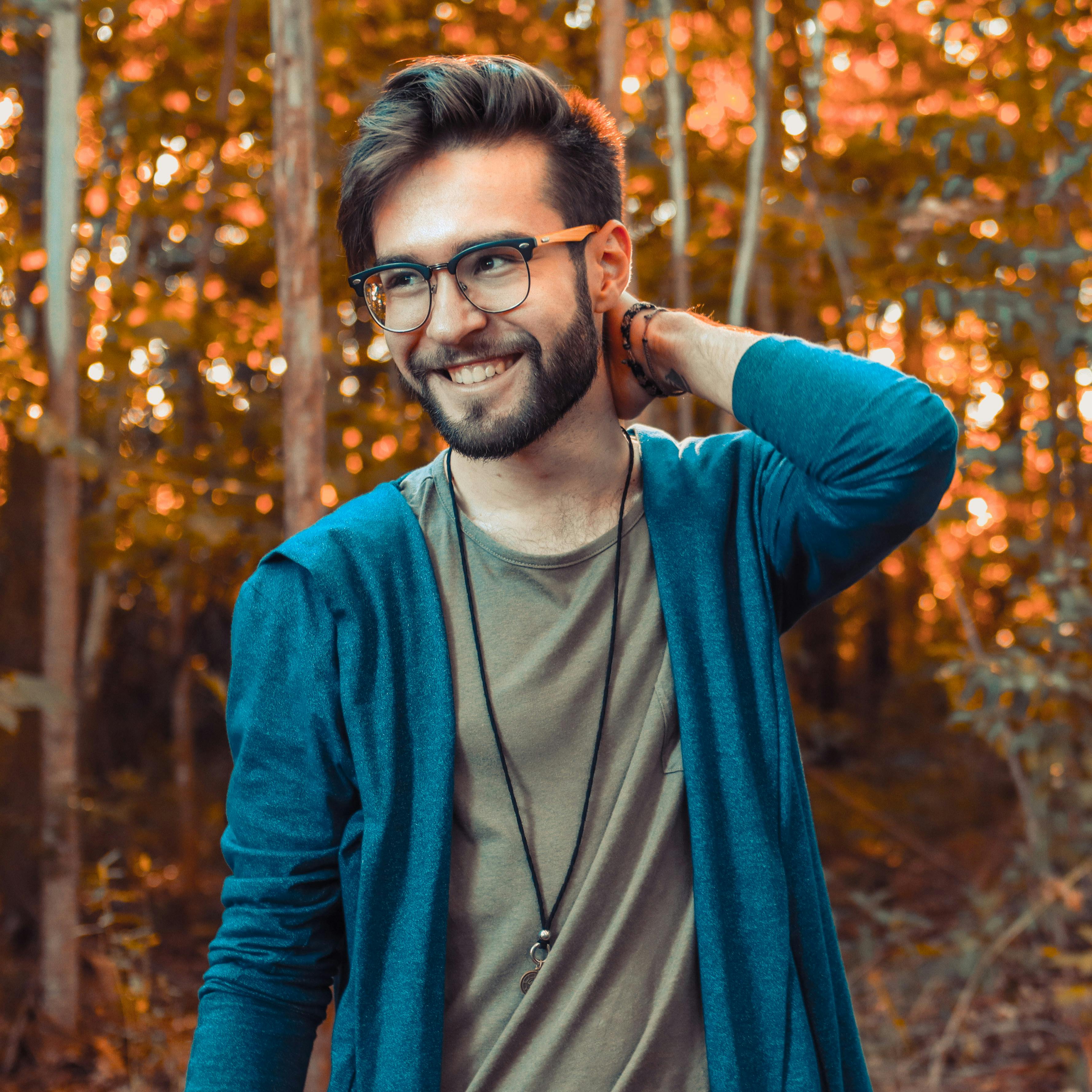 pexels-photo-2531553-2531553 Young man with glasses and beard smiling in a colorful autumn forest.